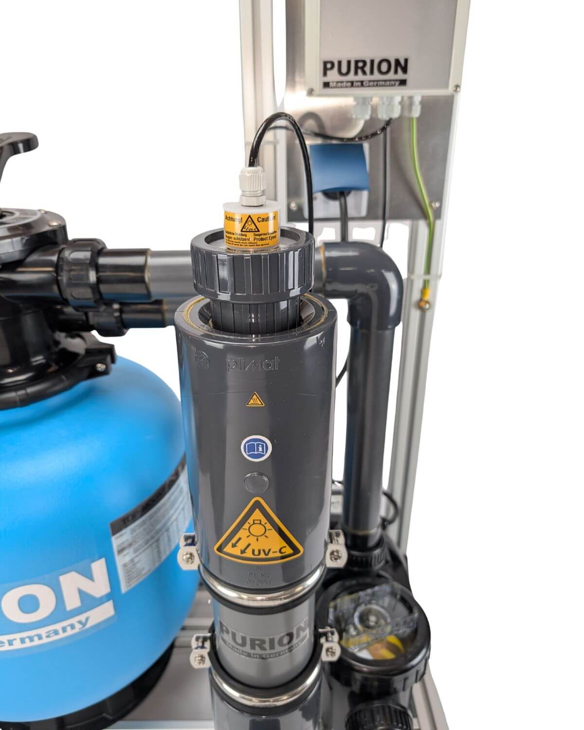 Κοντινή λήψη του PURION GmbH PURION Pool 40 PVC-U Basic με προειδοποιητικές πινακίδες απολύμανσης UV-C, μπλε αντλία, μαύρους σωλήνες και πίνακες ελέγχου - ιδανικό για την αποδοτική επεξεργασία νερού πισίνας σε εγκαταστάσεις πισίνας θαλασσινού νερού.
